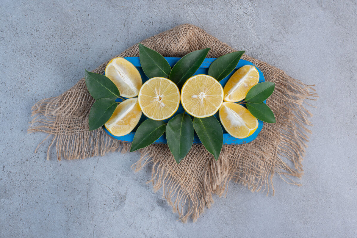 美味多汁的柠檬片和叶子放在大理石背景的蓝色盘子里营养美味拼盘