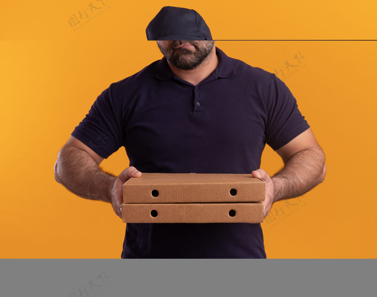 制服悲伤的中年送货员穿着制服 戴着帽子 看着隔离在黄色墙上的披萨盒送货披萨中年人