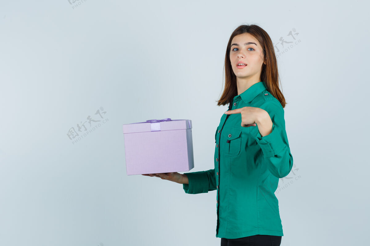 自然穿着绿色上衣 黑色裤子的年轻女孩拿着礼盒 指着礼盒 神采奕奕地看着 眼前一亮女人成人漂亮