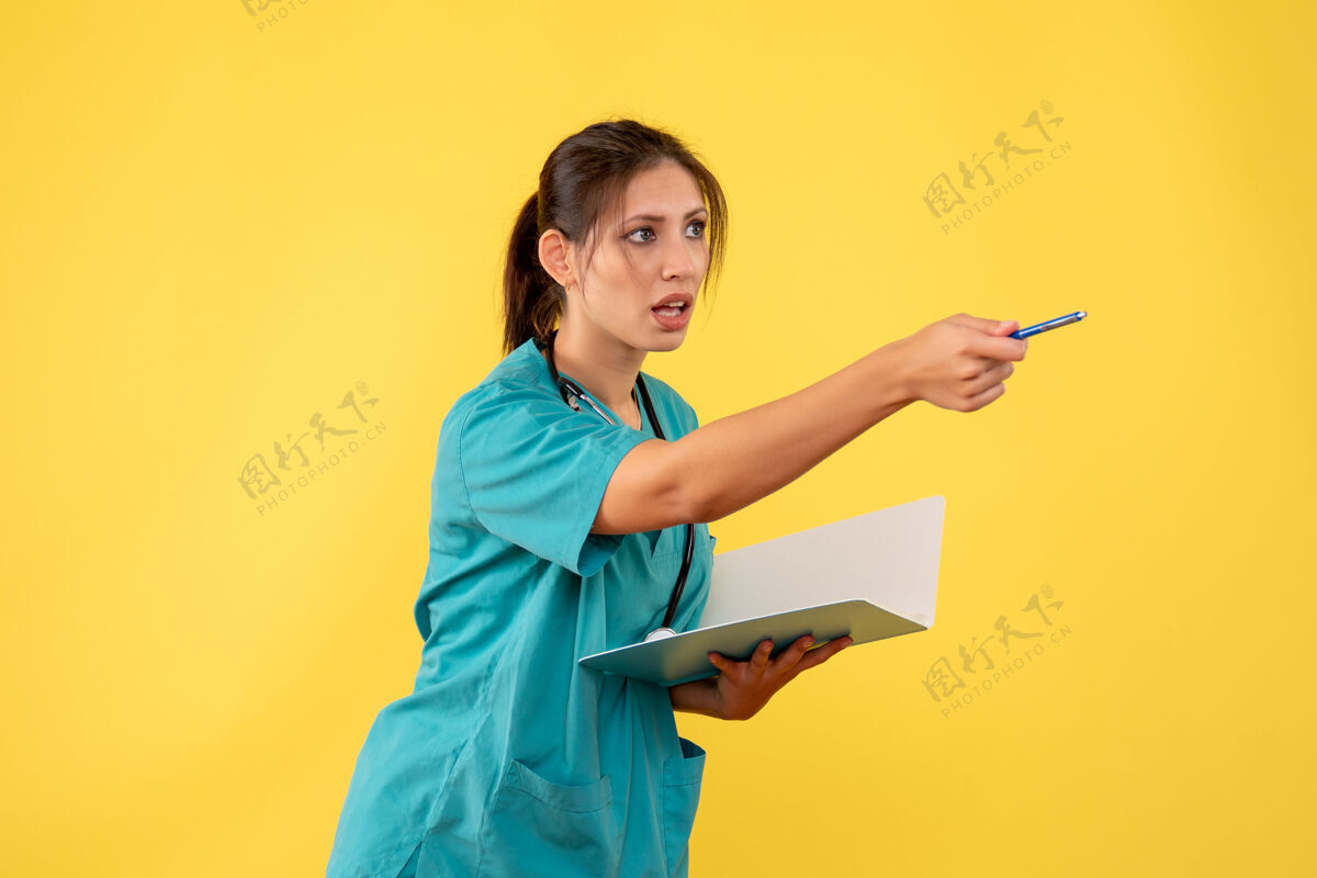 黄色前视图穿着医用衬衫的女医生拿着黄色背景的笔记笔记人物正面