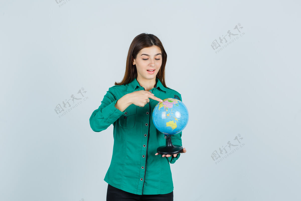 感性穿着衬衫的年轻女士拿着地球仪 指着地球仪 看上去很兴奋 正对着地球仪焦点水疗女人