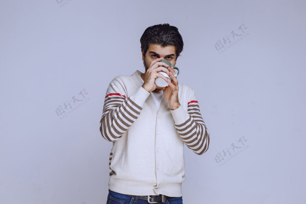 休闲穿着白衬衫的男人拿着咖啡杯 喝着咖啡 感觉精力充沛摄影人类热