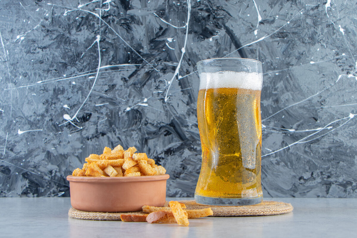 背景一碗面包屑和啤酒放在三角架上的玻璃杯里 大理石背景上美味玻璃杯盐