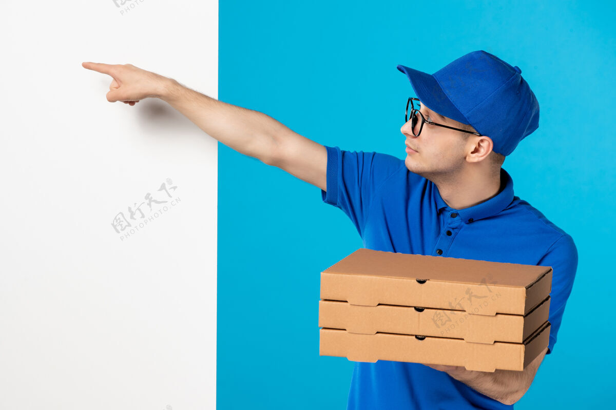 盒子身穿蓝色制服的男快递员的正面图 蓝色的是披萨盒头饰服务帽子