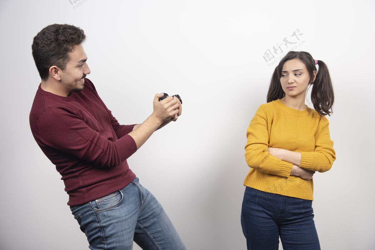 感情男人在白墙上给年轻女人拍照男人在一起两个人