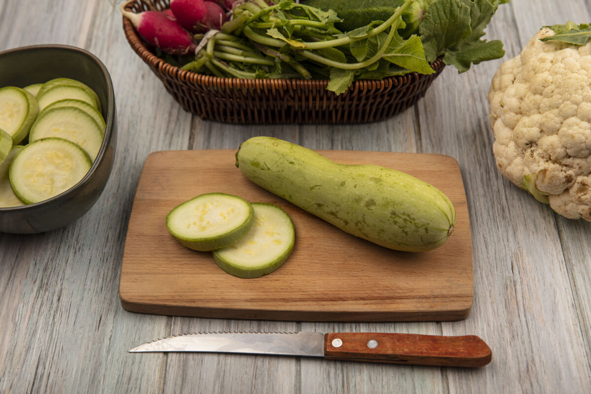 小胡瓜新鲜的绿色西葫芦的顶视图在一个木制的厨房板与菜花刀隔离在一个灰色的木制表面营养健康花椰菜