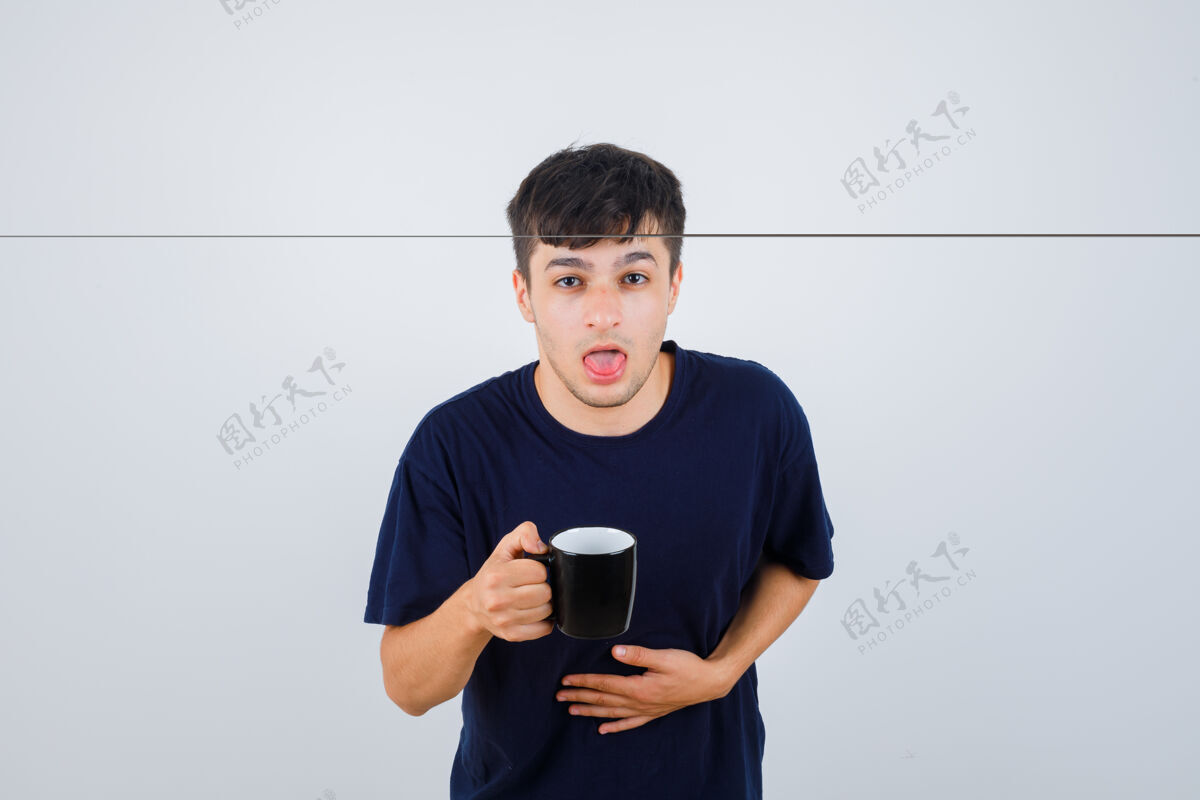 室内身穿黑色t恤的年轻人端着一杯茶感到恶心 看起来身体不适 正面视图疾病肌肉男性