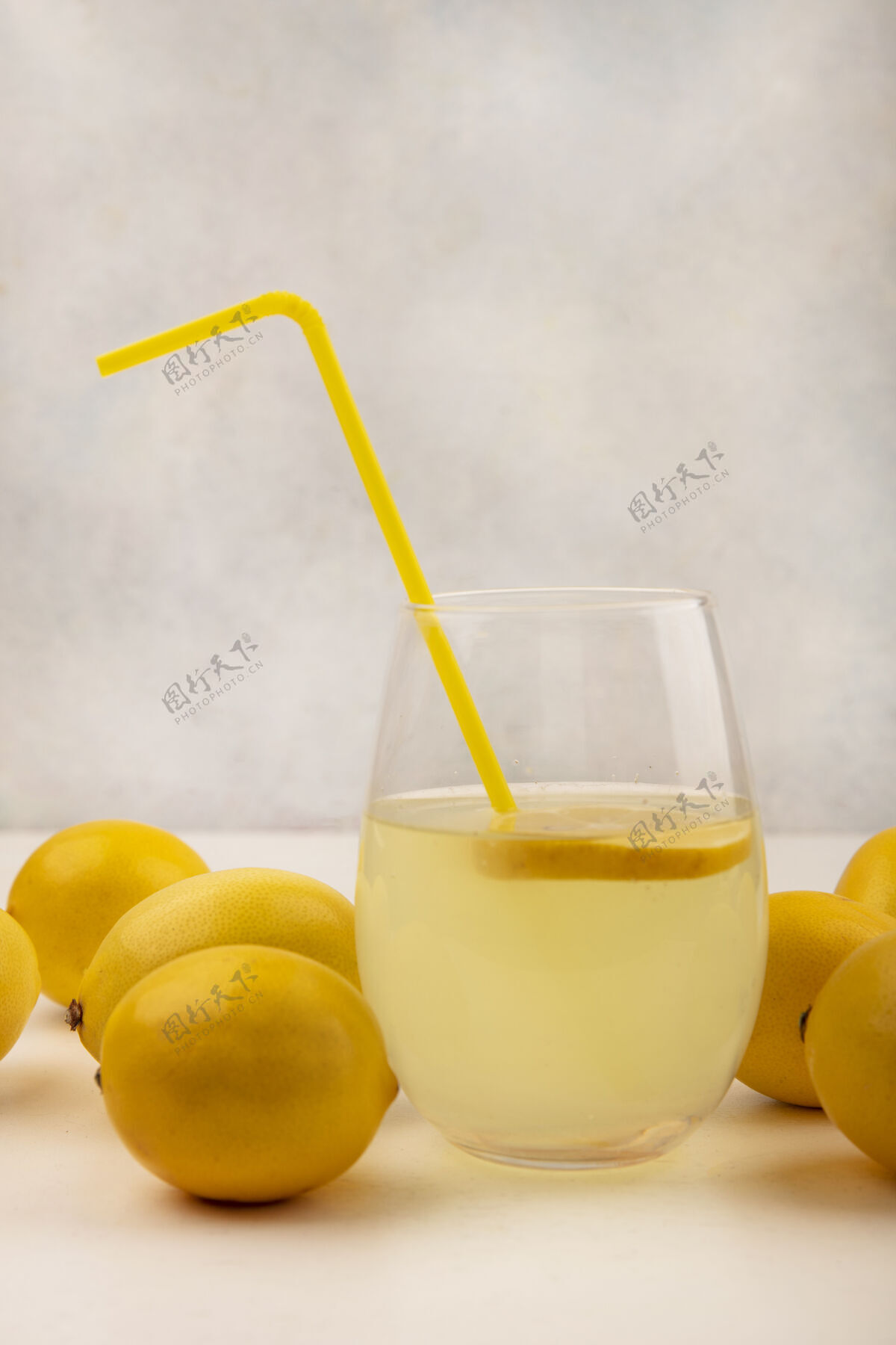 柠檬侧视图新鲜柠檬汁在一个玻璃与柠檬隔离在一个白色的表面饮食壁板柑橘