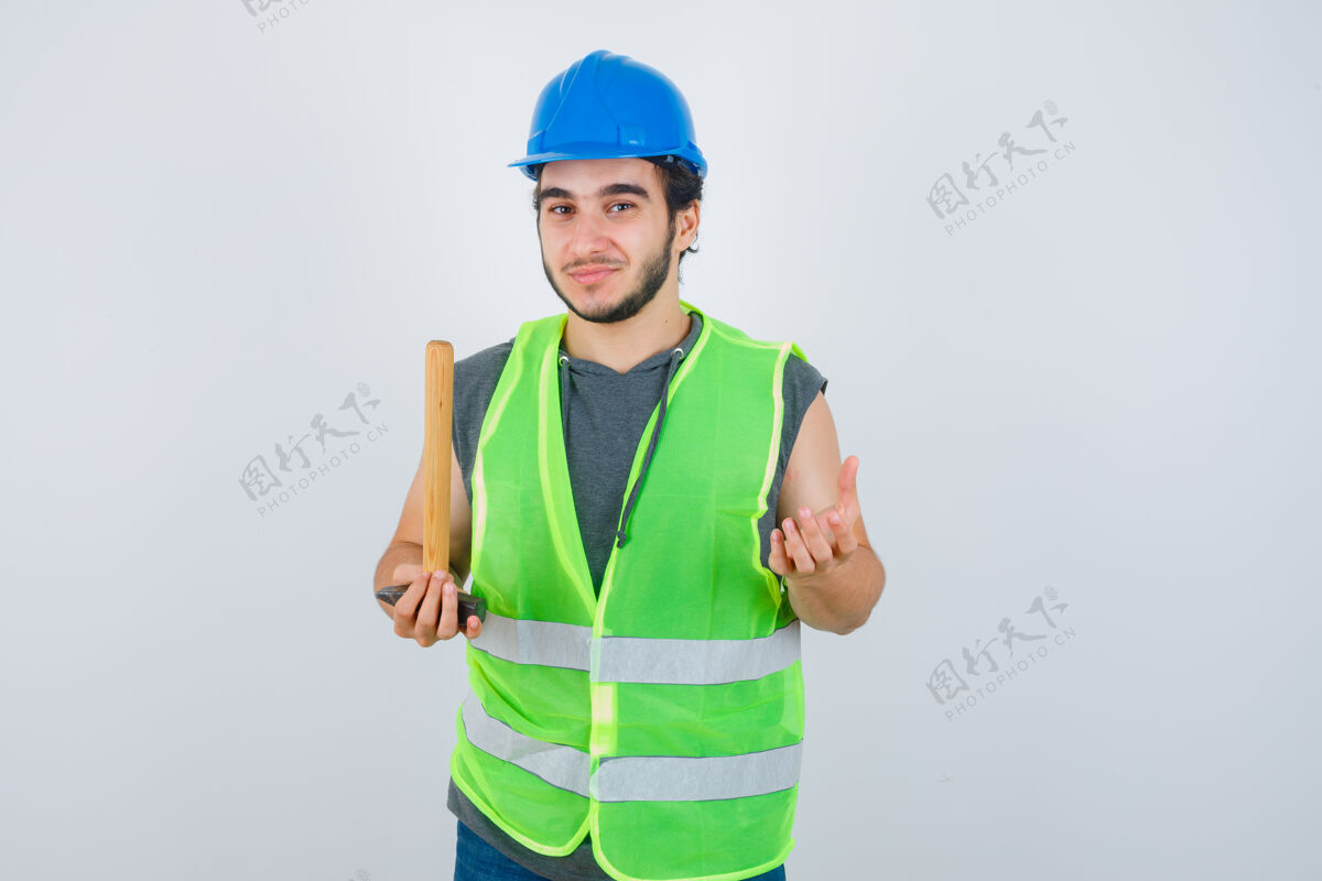 锤子年轻的建筑工人手里拿着锤子 手伸向一边 穿着工作服 看上去很快乐正视图男性自信持有