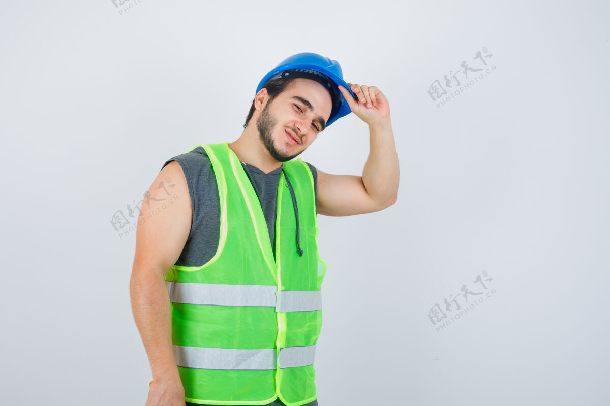 前面年轻的建筑工人手拿头盔 穿着工作服 看上去很高兴前视图休闲享受建设者