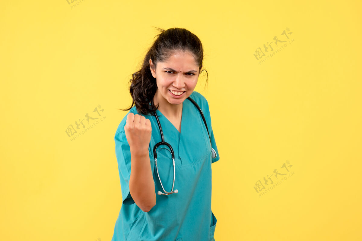 健康正面图身着制服的年轻女医生站在黄色背景上 欣喜若狂医学制服医院