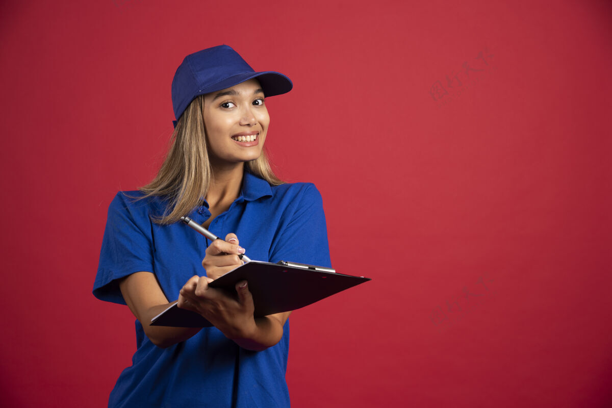 铅笔身着蓝色制服 面带微笑的女人用铅笔在剪贴板上写字模型女人帽子