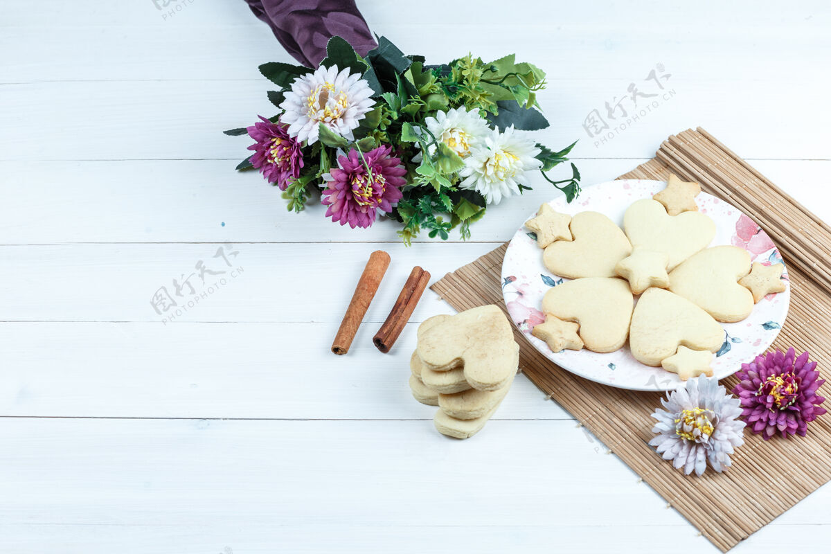 堆叠高角度观看心形和星型饼干 鲜花放在肉桂垫上饼干烘焙巧克力