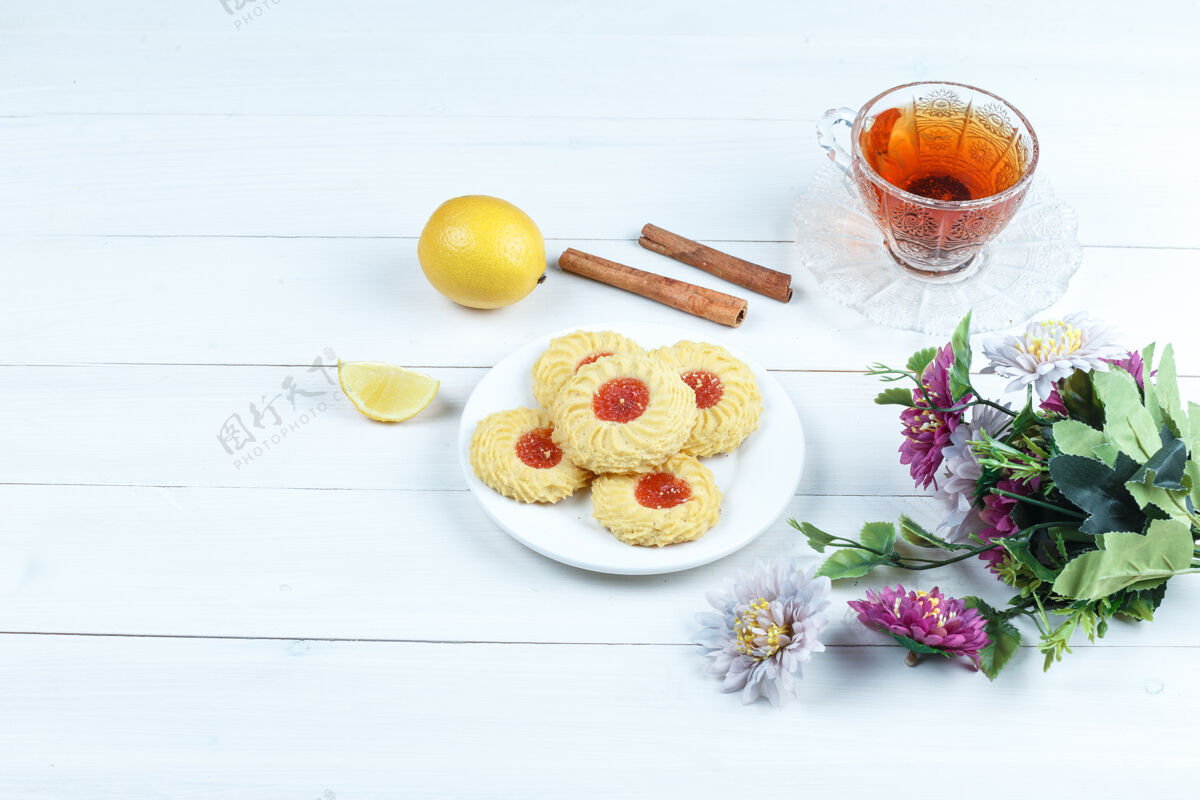 香气一些饼干 一杯肉桂茶 柠檬 花在白色木板背景上 高角度观看柠檬早餐花