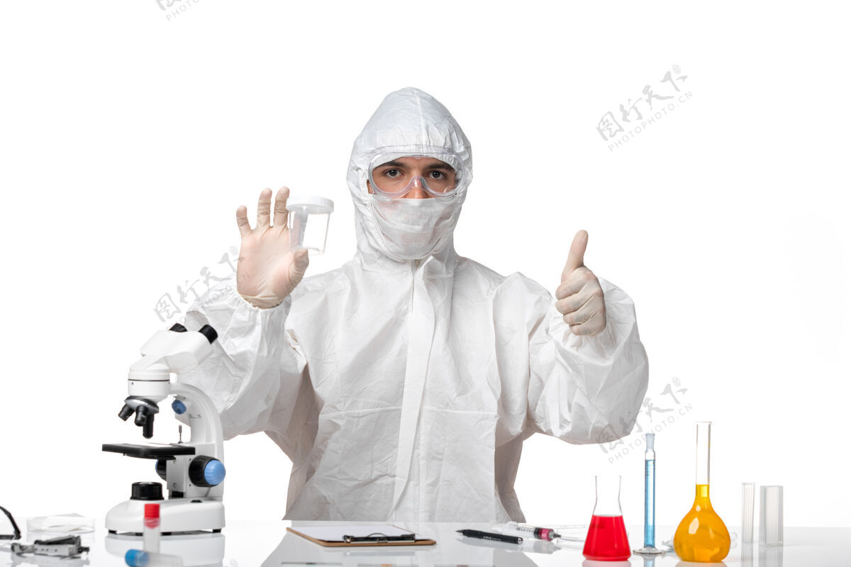 药品正面图穿着防护服的男医生拿着烧瓶在浅白的空间里专业人员套装诊所