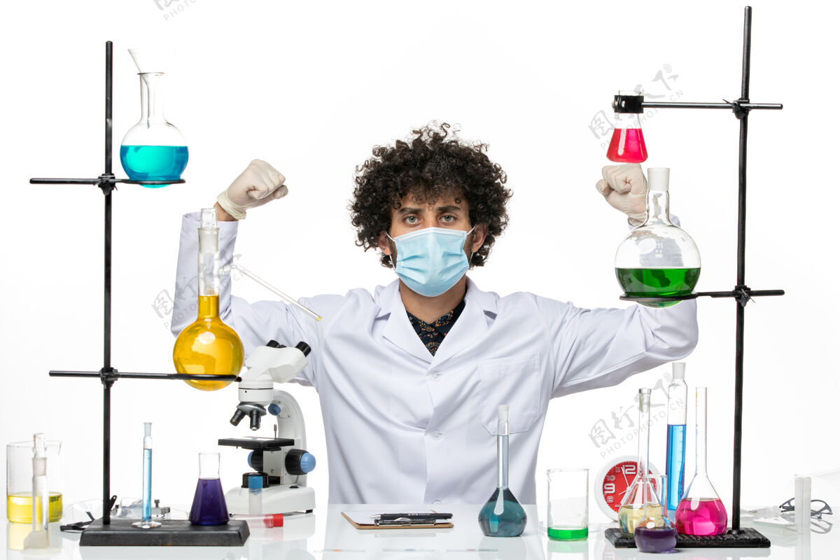 男性正面图：男药剂师穿着医疗服 戴着口罩 正坐在溶液中 在空白处弯曲男性化学家病毒实验室