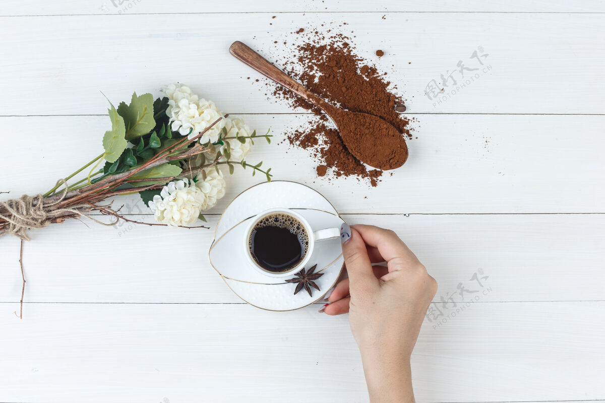 咖啡因一套磨碎的咖啡 鲜花 香料和女性手拿着一杯咖啡的木制背景平放杯子豆类摩卡咖啡