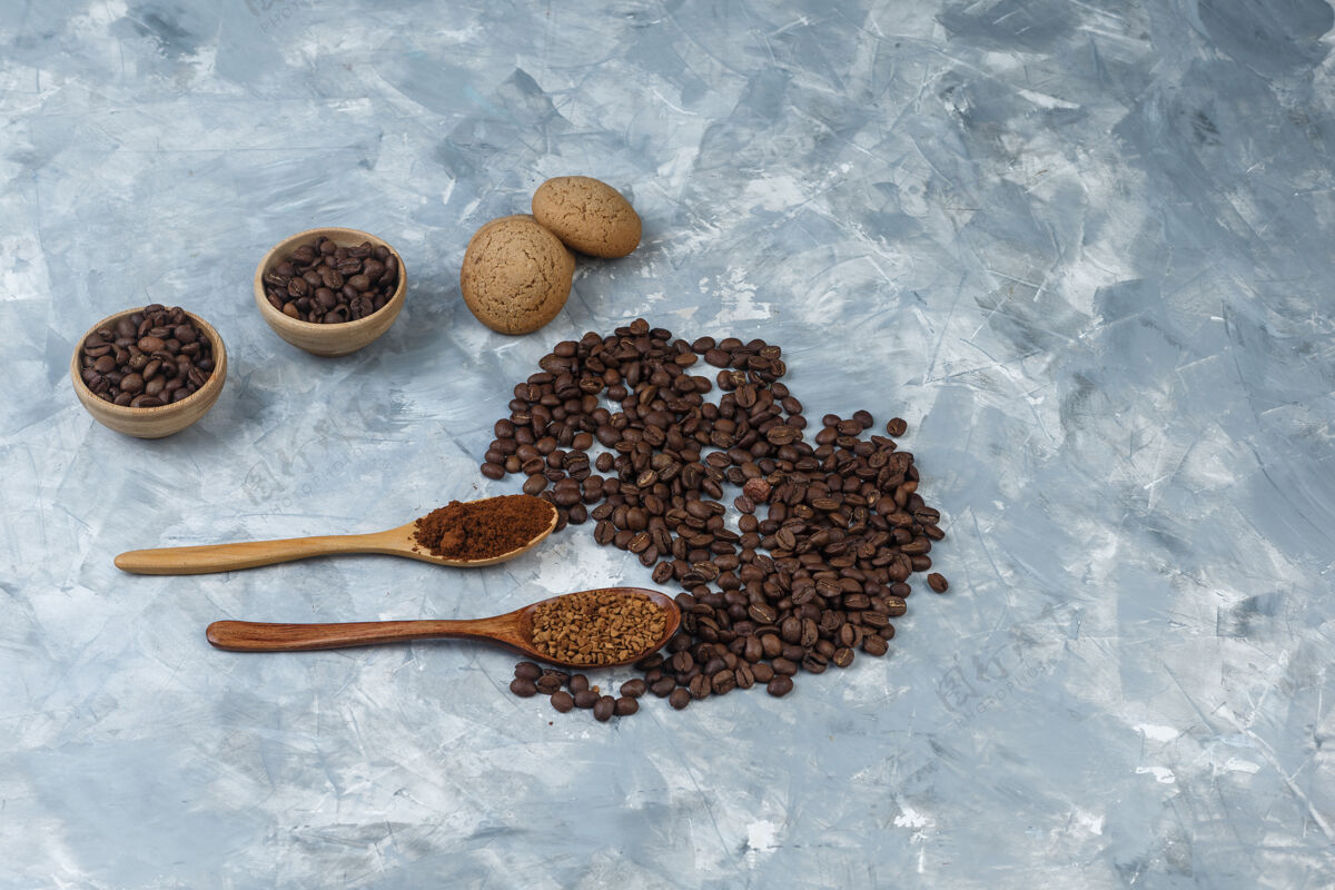 咖啡一套饼干 速溶咖啡和咖啡粉装在木制勺子里 咖啡豆装在浅蓝色大理石背景的碗里特写女性拿铁勺子