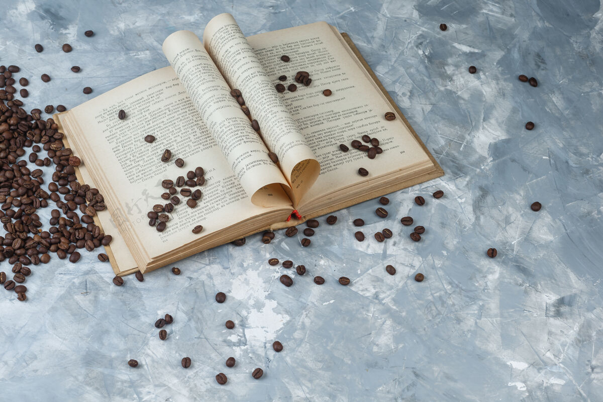 豆子一些咖啡豆与浅蓝色大理石背景上的书 高角度观看马克杯咖啡香气