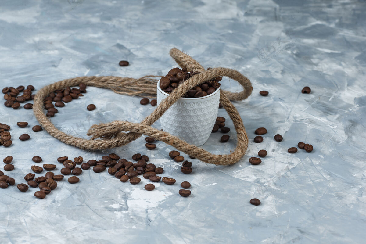 摩卡咖啡咖啡豆在一个白色的杯子里 在灰色的石膏背景上用绳子高角度观看食物配料热的