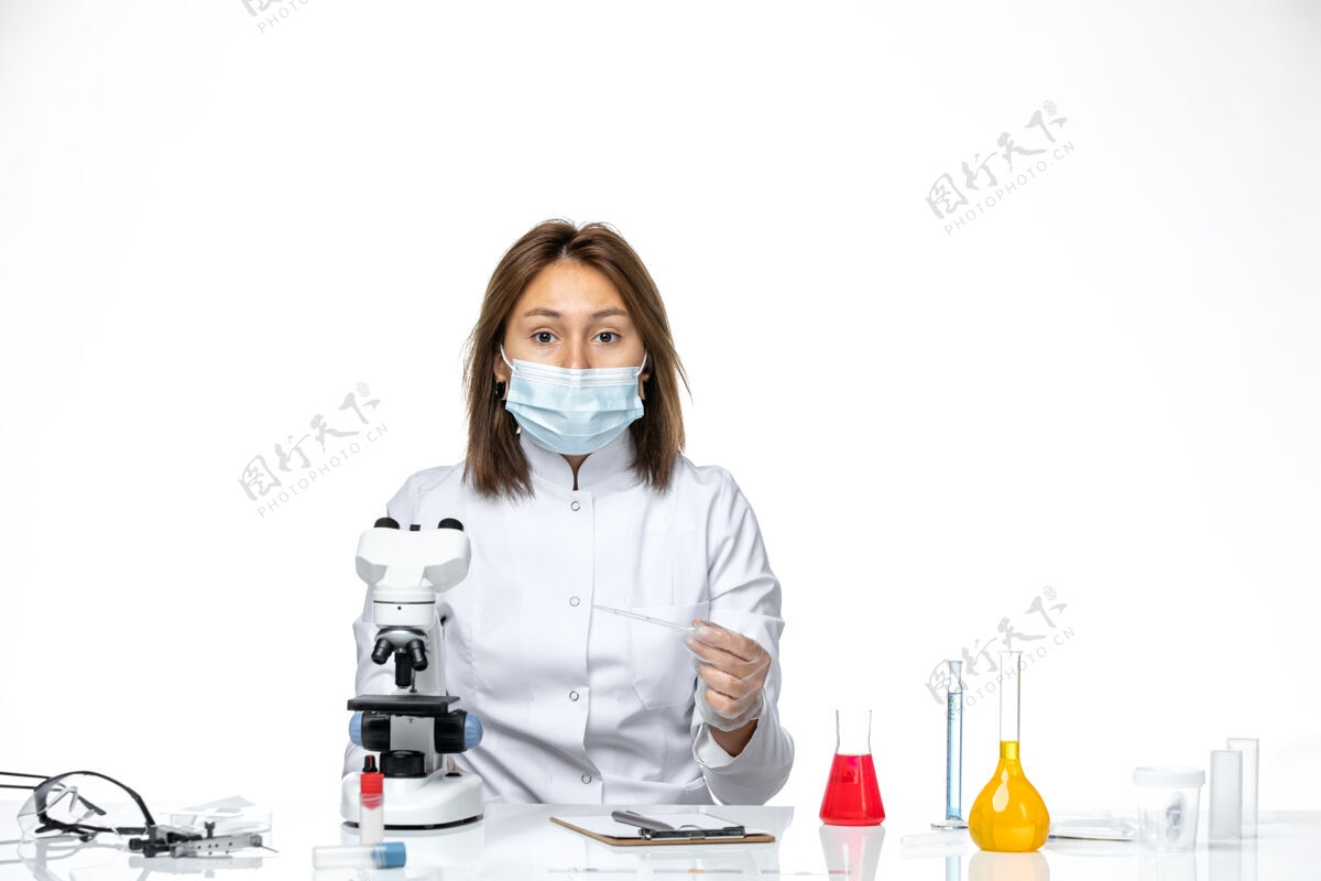显微镜在白色办公桌上使用显微镜 看到穿着白色医疗服 戴着口罩的女医生套装家庭主妇使用