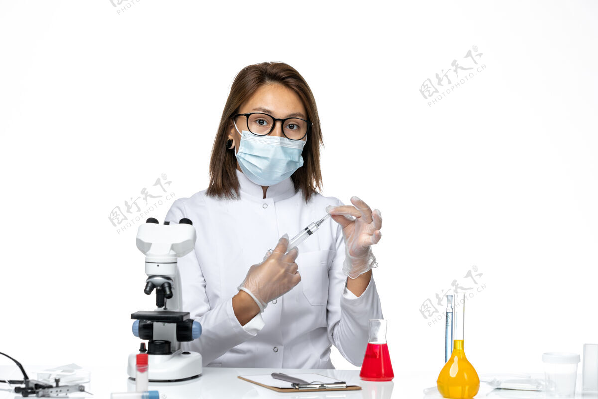 专业前视图：女医生穿着白色医疗服 戴着口罩 因为冠状病毒在白色的空间里注射套装实验室外套正面
