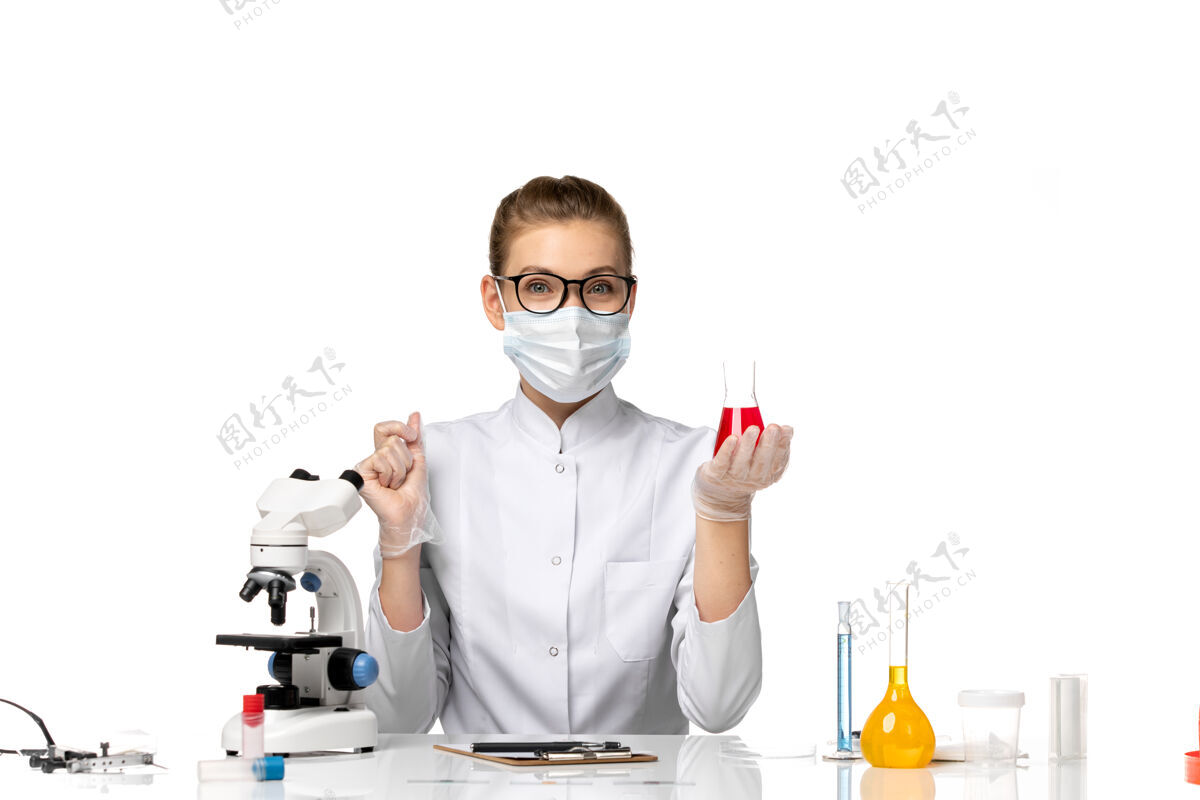 实验室外套正面图：女医生穿着医疗服 戴着面罩 因为科维德在白色办公桌上用溶液工作口罩病毒外套