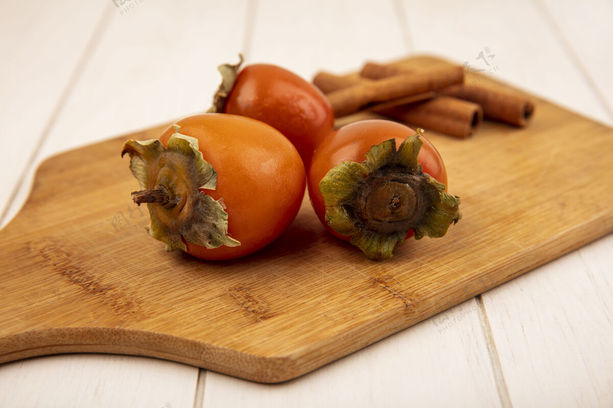 水果软柿子在木制厨房板上的俯视图 白色木质表面上有肉桂棒配料健康新鲜