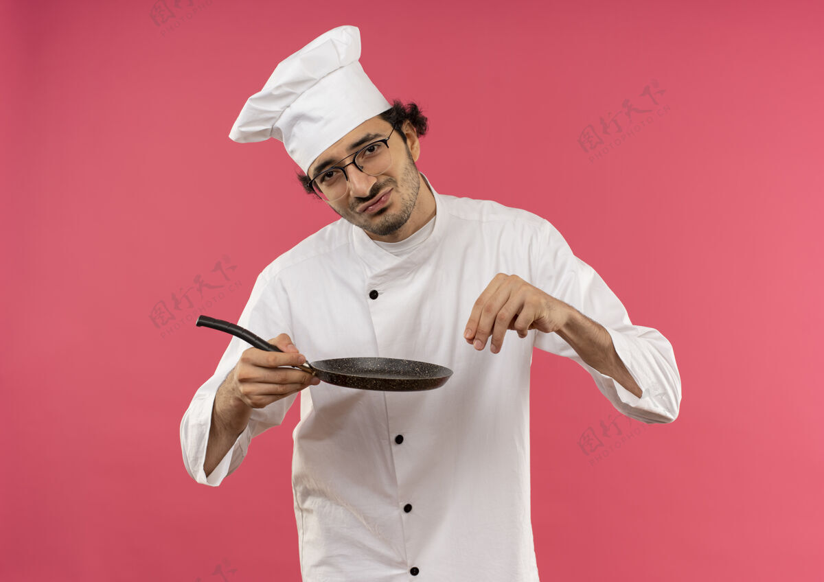 盐年轻的男厨师穿着厨师制服戴着眼镜拿着煎锅假装撒盐洒薯条男