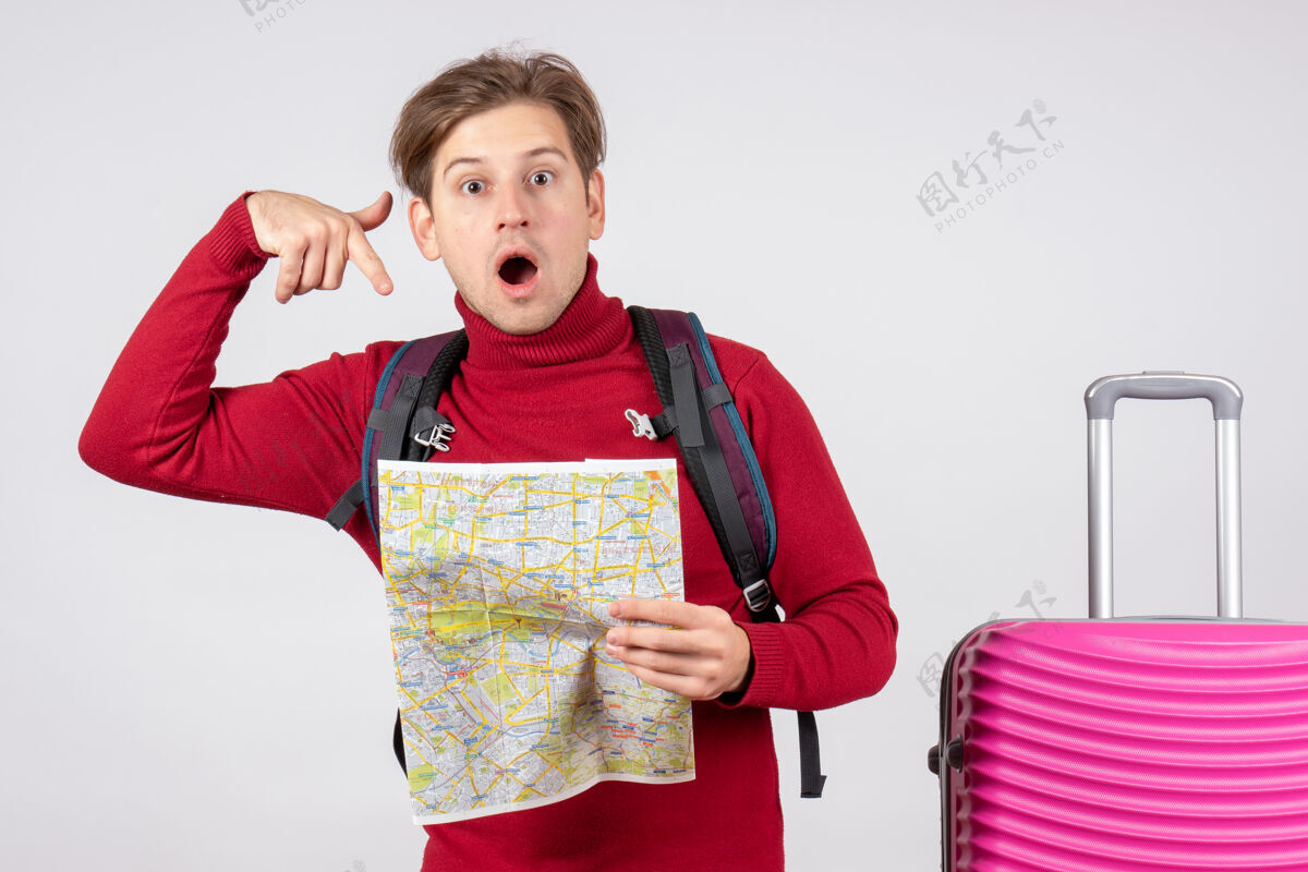 夏天男游客的正面图 白色墙上有背包和地图背包欢呼假期