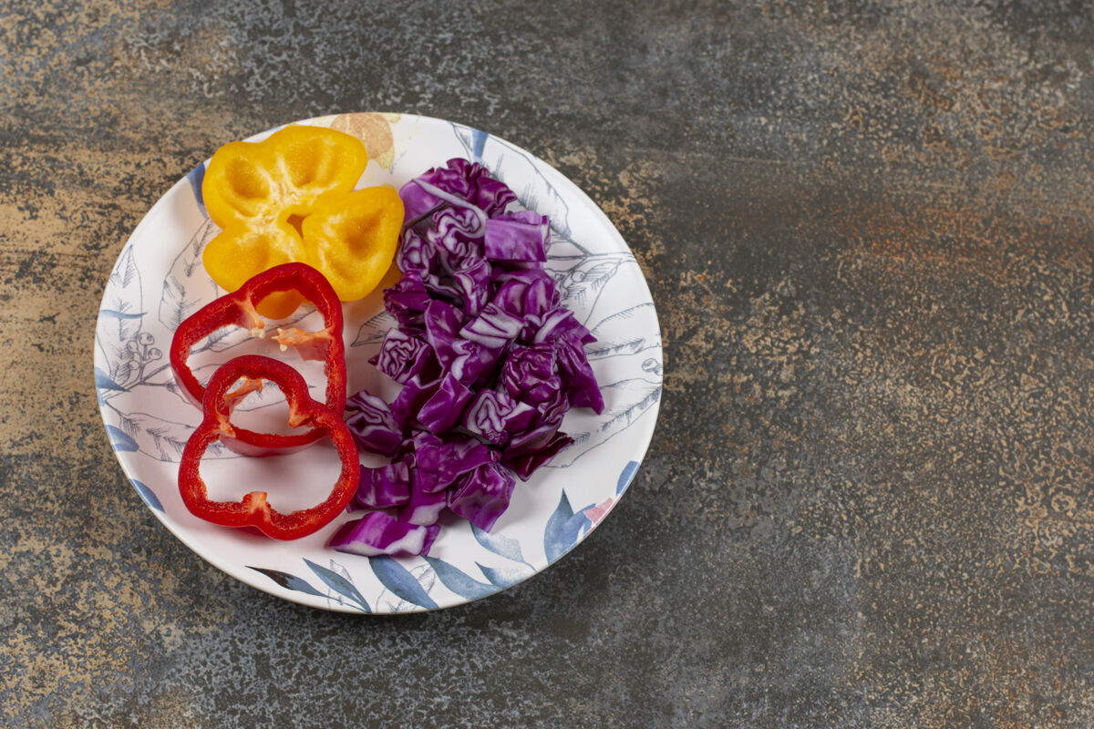 新鲜把甜椒片和红卷心菜切碎放在盘子里 放在大理石表面美味生的美味