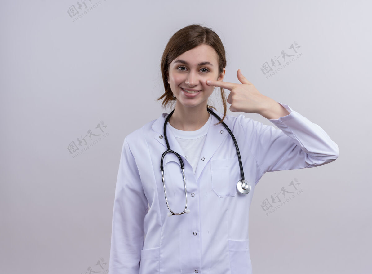 女人微笑着的年轻女医生穿着医用长袍 听诊器把手指放在脸颊上 隔离着白色的墙壁上 留着复印空间面颊女人听诊器
