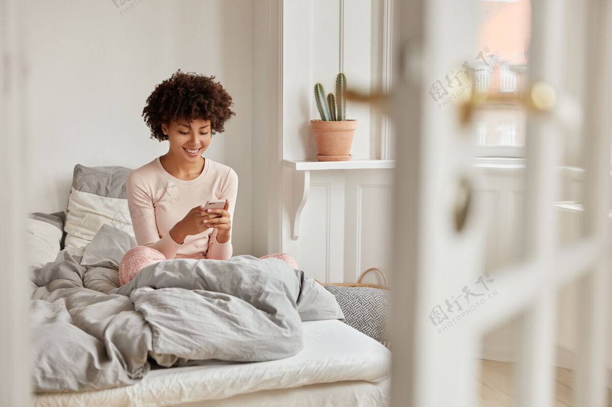 内容积极的黑皮肤女性通过手机阅读网站上的网络出版物电话姿势打字