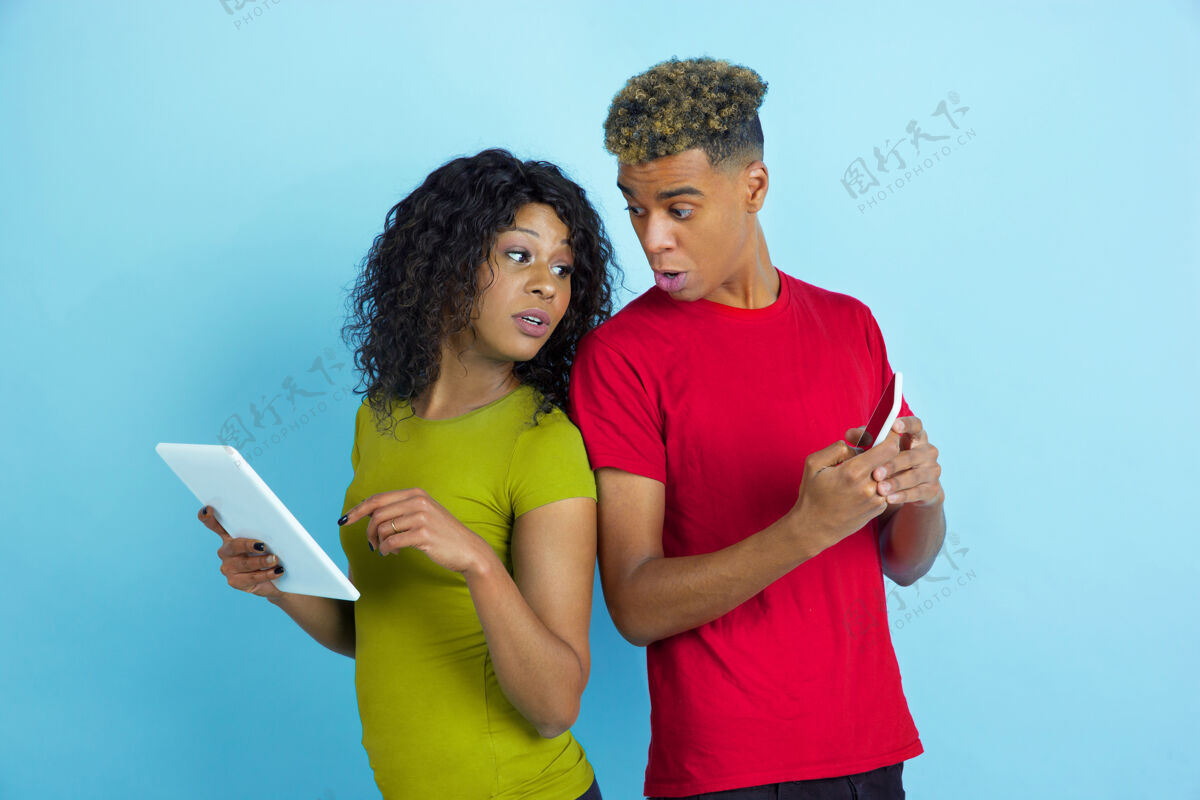 黄色年轻动情的非裔美国男女穿着五颜六色的衣服 用小玩意 偷窥着蓝b上的屏幕蓝色休闲指向