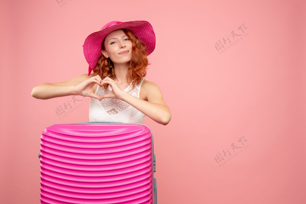 时尚粉色墙上带着粉色包的女游客正面图度假情感航行