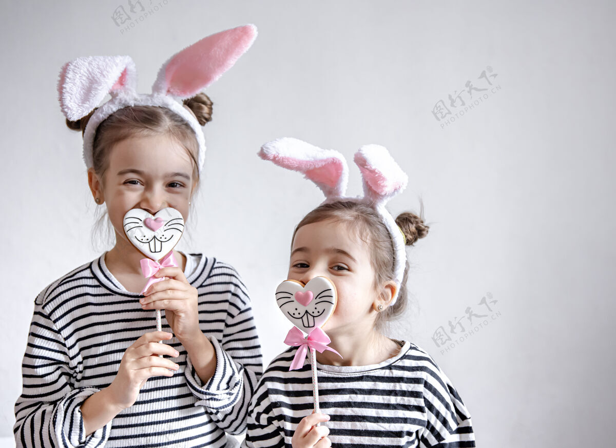 饼干有趣的小女孩 头上戴着复活节耳朵 树枝上放着复活节姜饼孩子治疗举行