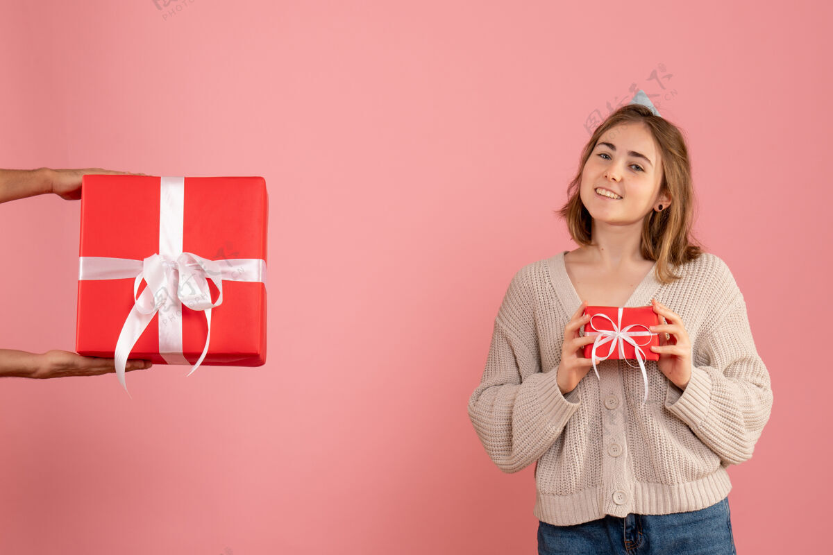 粉红色年轻的女性拿着圣诞礼物 接受粉色的男性礼物举行圣诞节人