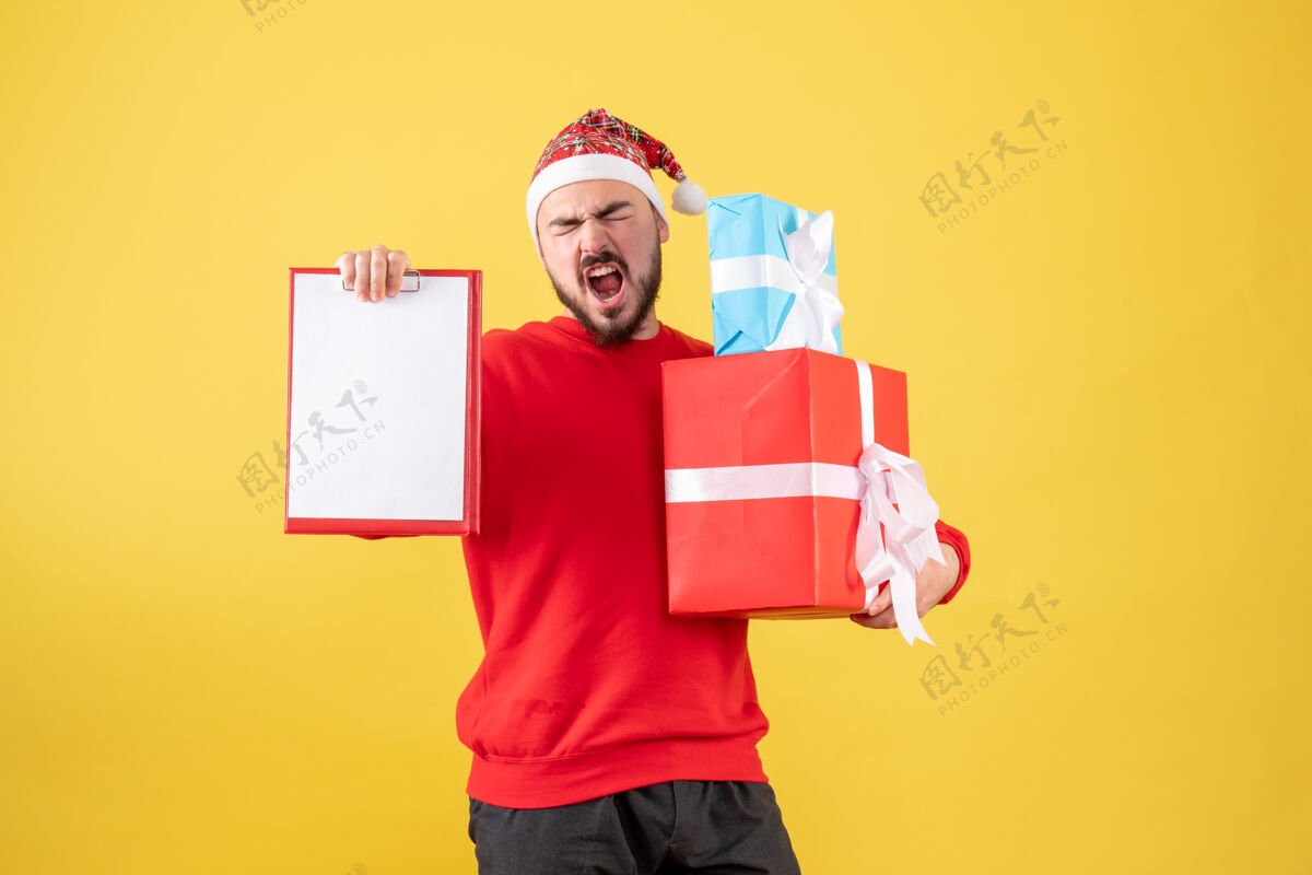 圣诞节前视图年轻男性与圣诞礼物和黄色背景上的注意年份礼物礼物