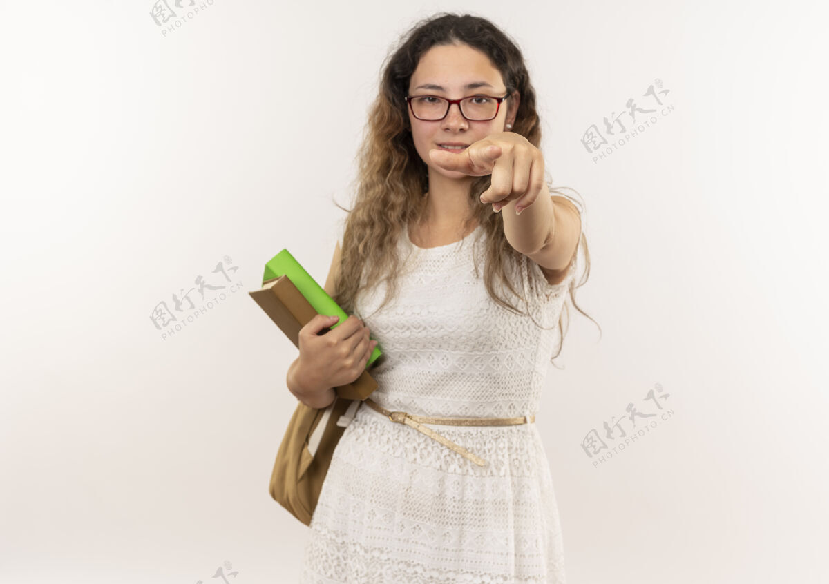眼镜自信的年轻漂亮的女学生戴着眼镜 背着书包 拿着书 孤立地指向白色的空白处漂亮指向女学生