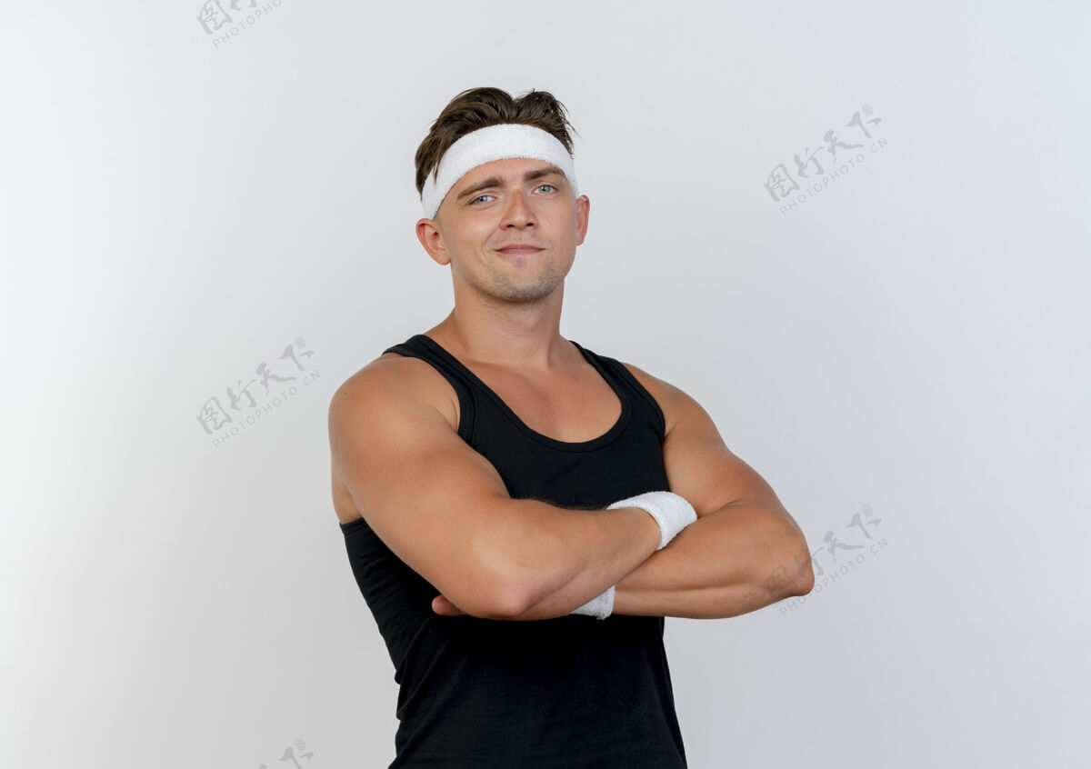 年轻自信的年轻帅气的运动型男人戴着头带和腕带 站着封闭的姿势 与白色隔离 留有复制空间复制腕带头带