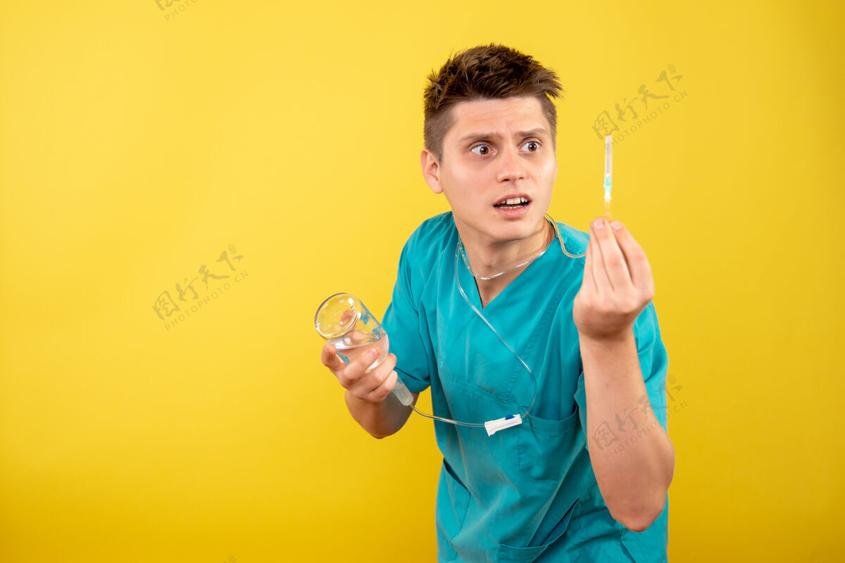 医疗正面图身穿医疗服的年轻男医生拿着黄色背景上的滴管滴管高尔夫球手西装