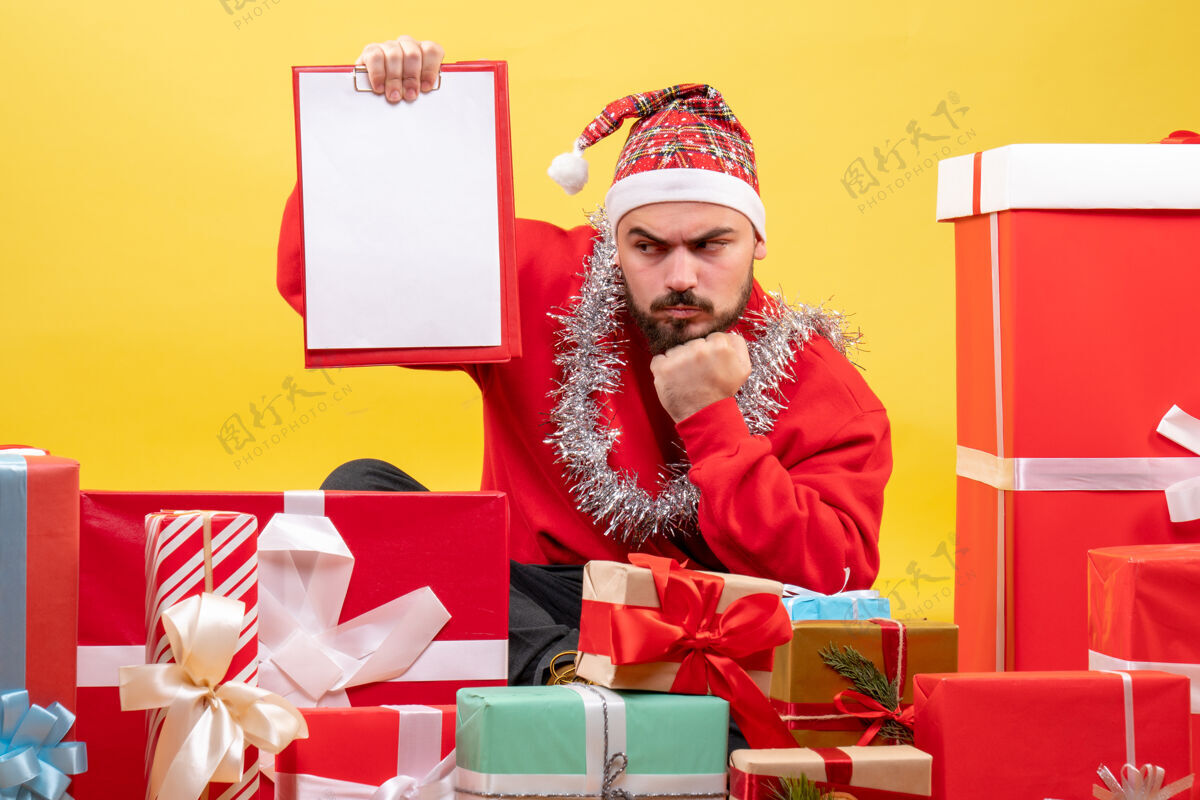 雪正面图：年轻男性围坐在黄色背景的圣诞礼物旁礼物盒子年轻的男性