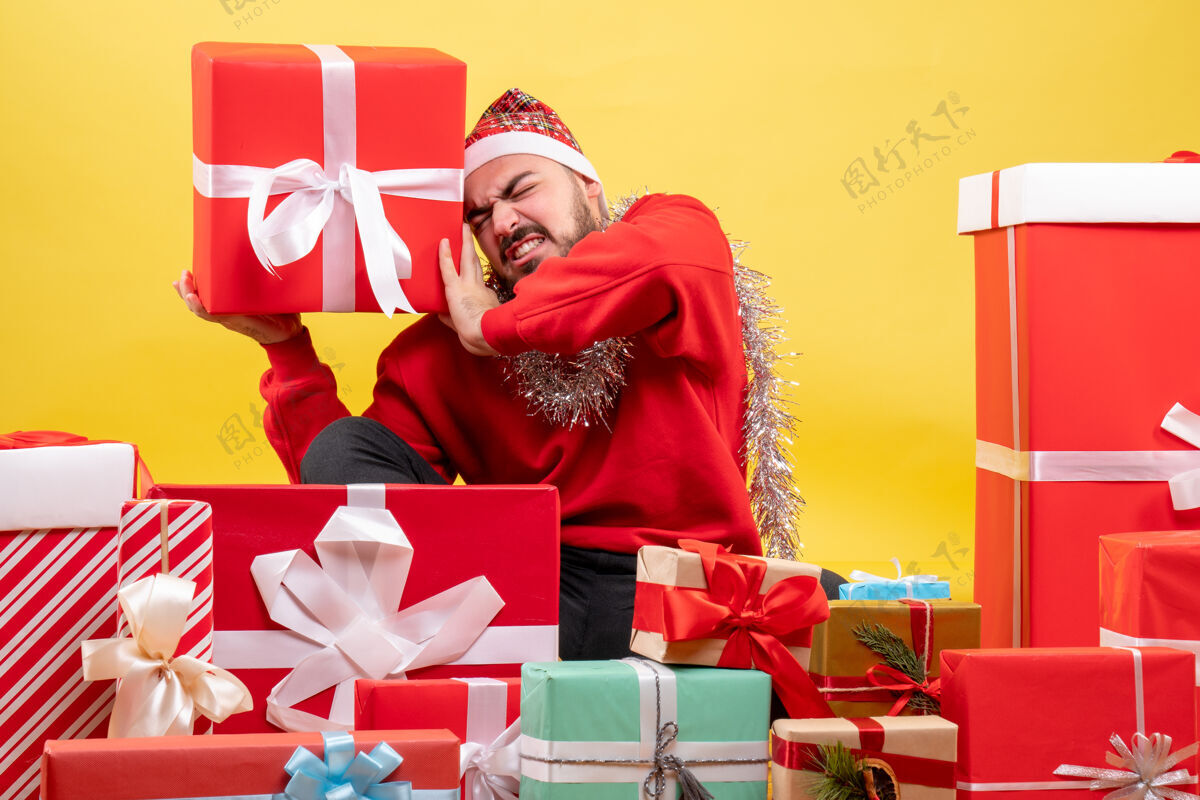 圣诞节正面图：年轻男性围坐在黄色背景上的圣诞礼物旁欢呼体育场礼物