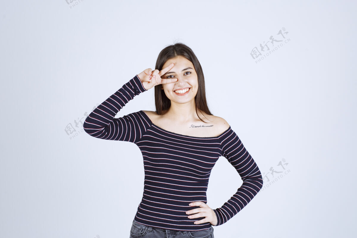 女性穿条纹衬衫的年轻女子发出和平信号休闲微笑女人