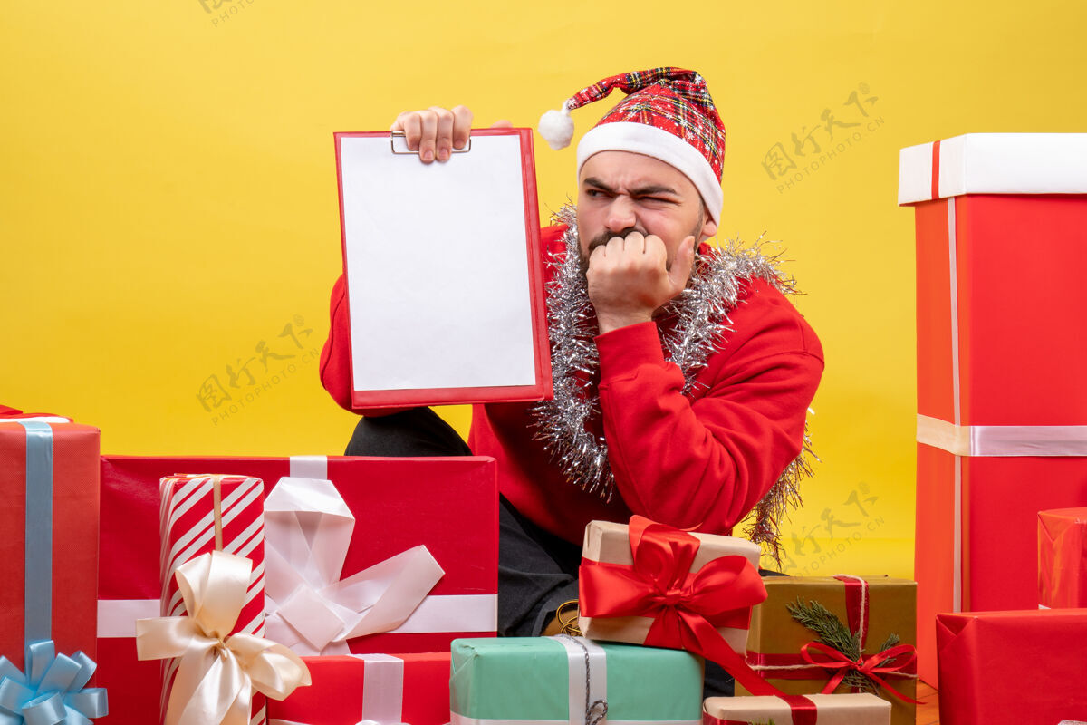坐着正面图：年轻男性围坐在黄色背景的圣诞礼物旁人年情绪