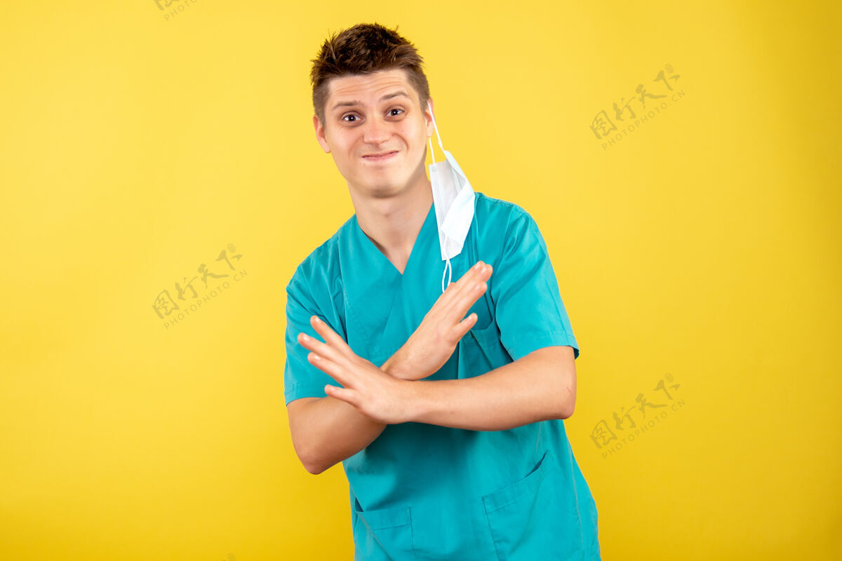 高尔夫球手正面图身着医疗服的年轻男医生 黄色背景上有无菌面罩健康绝育医学