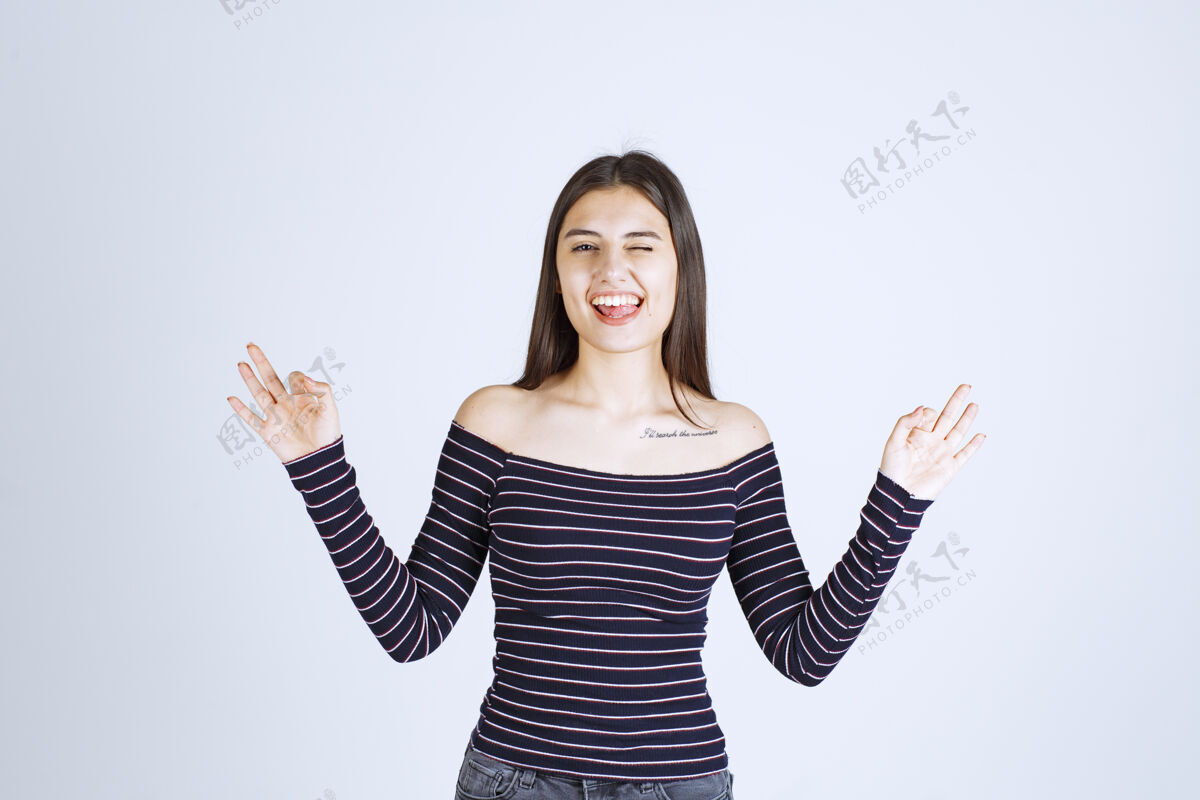 好穿条纹衬衫的年轻女子展示着手牌微笑人同意