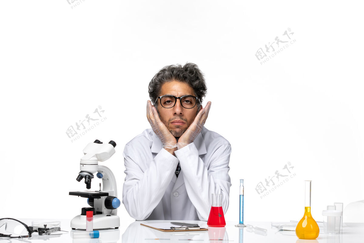 技术人员正面图穿着特殊白色西装的中年科学家围坐在桌子旁 拿着解决方案化学实验周围