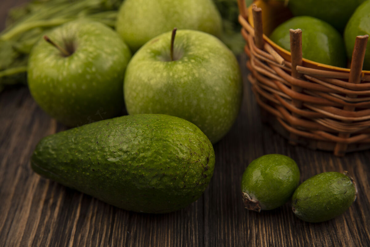 新鲜一桶新鲜的酸橙和绿色的苹果的俯视图就像一个木墙上孤立的鳄梨玻璃飞珠木材