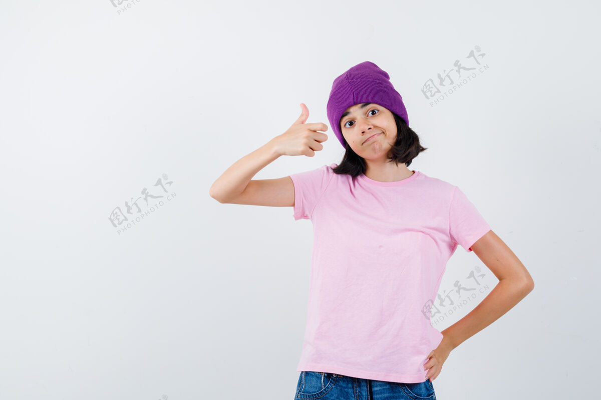 女孩十几岁的女孩穿着粉色t恤 小豆豆 牛仔裤 大拇指朝上 手放在腰上 看起来很高兴 正面视图表情青少年青年